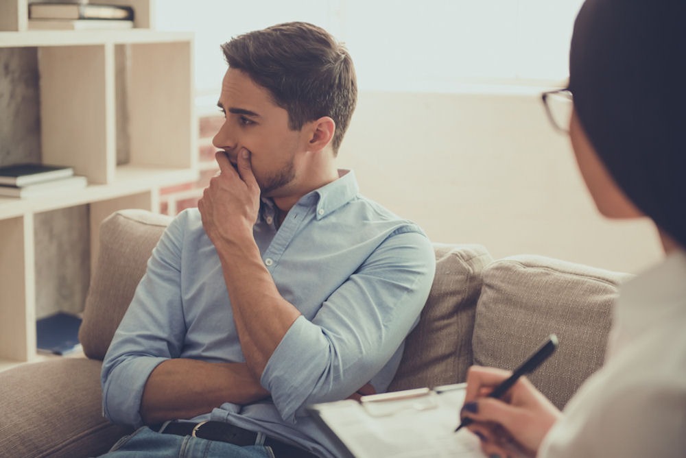 a man talking to his therapist about his trauma and alcohol addiction