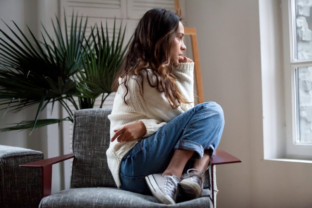 Sad thoughtful girl sitting on chair suffering from ptsd