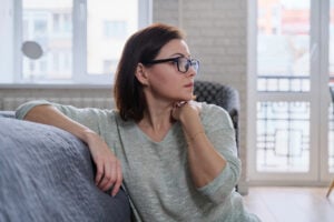 Woman sitting thoughtfully at home reflecting on depression and unresolved trauma symptoms