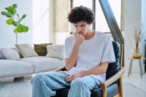 Young man sitting alone reflecting emotional distress related to fentanyl use and addiction recovery