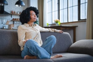 Woman sitting thoughtfully at home reflecting on trauma, emotional stress, and recovery healing